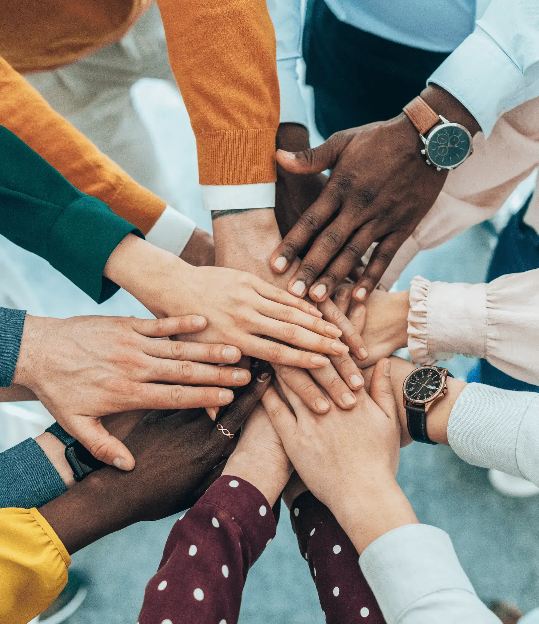 Diverse group joining hands in unity and teamwork.